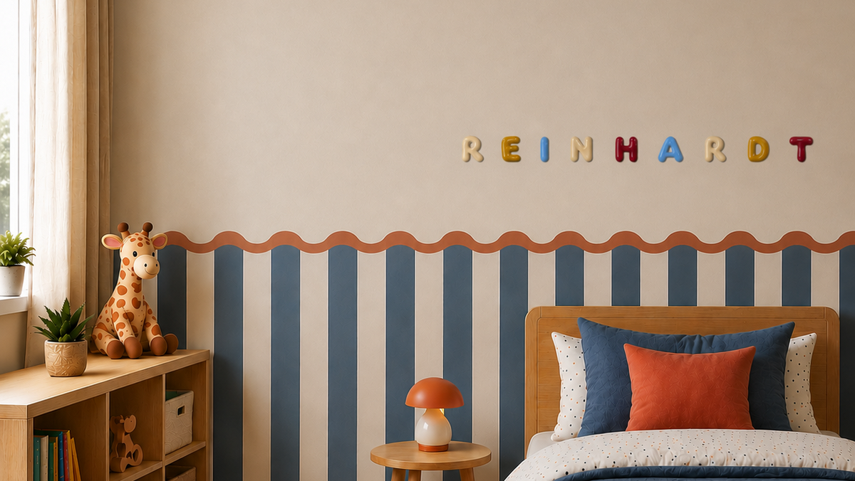 A styled children's bedroom featuring a wooden bed with blue and orange bedding, a striped blue and white wall, and colorful wooden letters spelling 'REINHARDT' on the wall.