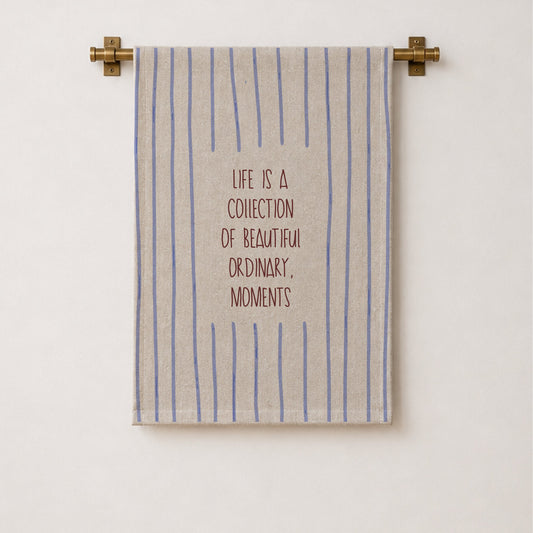 A striped wall hangingwith the quote 'LIFE IS A COLLECTION OF BEAUTIFUL ORDINARY. ORDINARY.